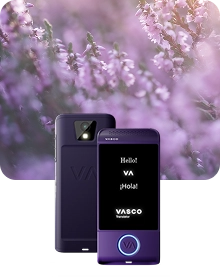 A product showcase image featuring a purple Vasco Translator device from two angles against a dark, textured fabric background. The device on the left shows the back view, highlighting a camera lens with a flash and an embossed 